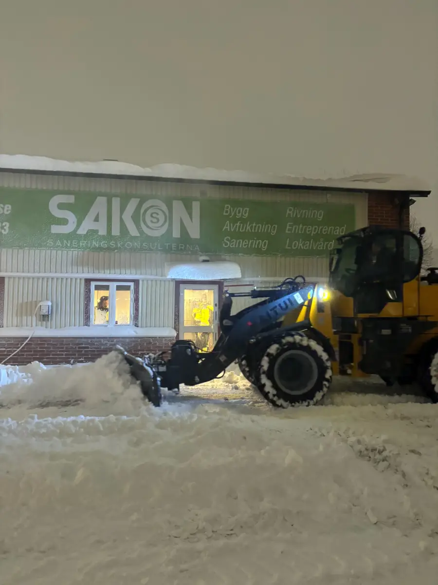Frontlastare som snöröjer en parkering vintertid — SAKON Entreprenad